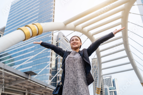 successful business woman with arms raised in city