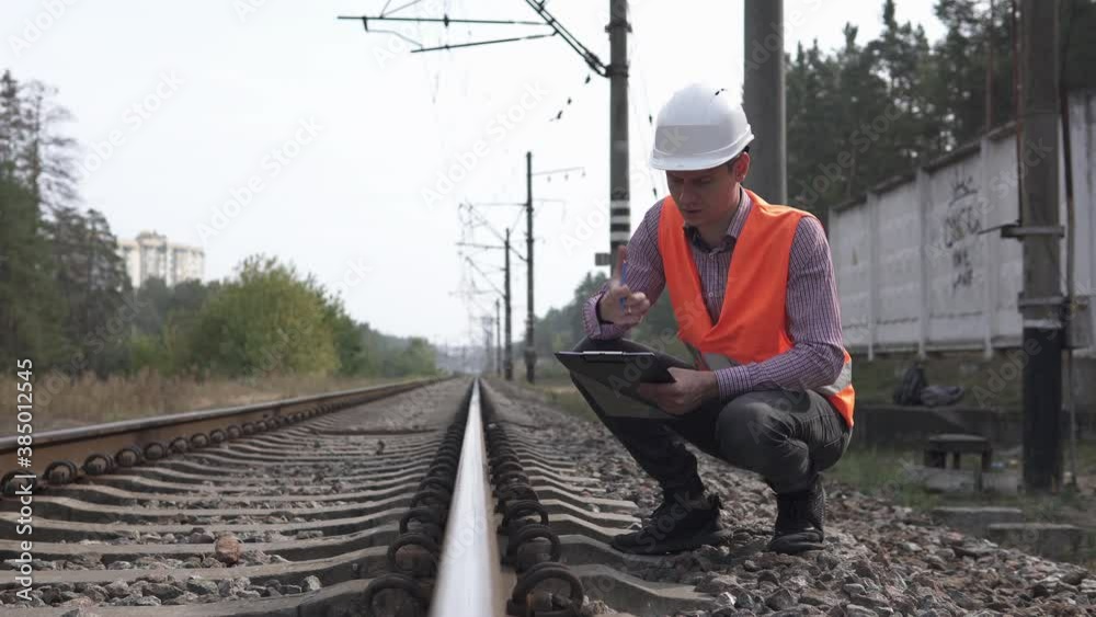 Railway engineer counts the number of sleepers and writes in a notebook.Railroad maintenance concept. Railway engineer counts the number of sleepers and writes in a notebook.Railroad maintenance concept.
