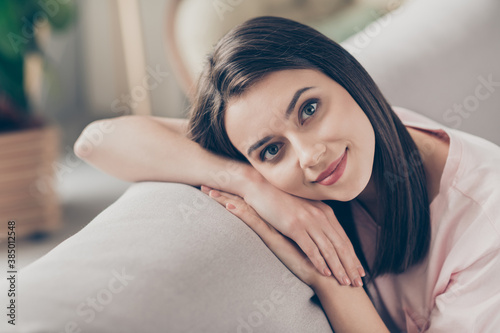 Photo portrait of cute girl lying on hands on sofa back indoors