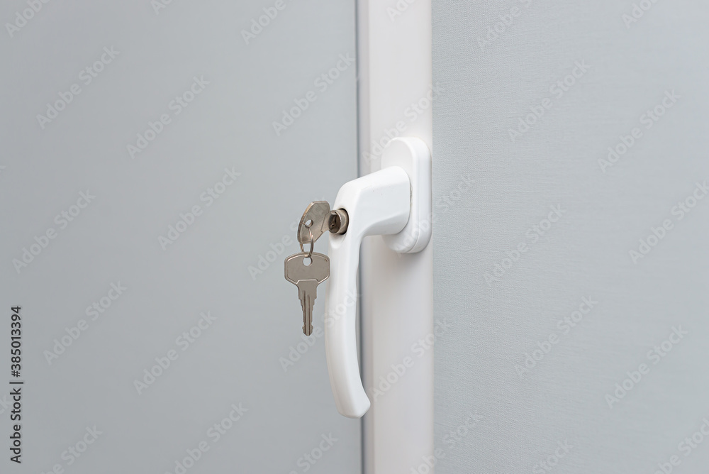 The concept of protecting a child from falling out of windows. Handle with a lock on the window. The concept of protecting a child from falling out of windows. Handle with a lock on the window.