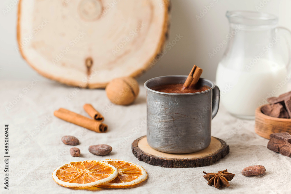 Hot chocolate in a metal mug with a cinnamon stick on the tablecloth. Copy space Hot chocolate in a metal mug with a cinnamon stick on the tablecloth. Copy space