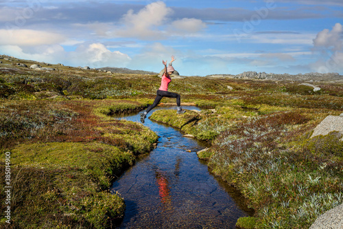 Woman run free jumping little meandering  stream in high country photo