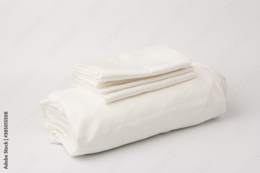 Stack of clean bed sheets on white  background, closeup.