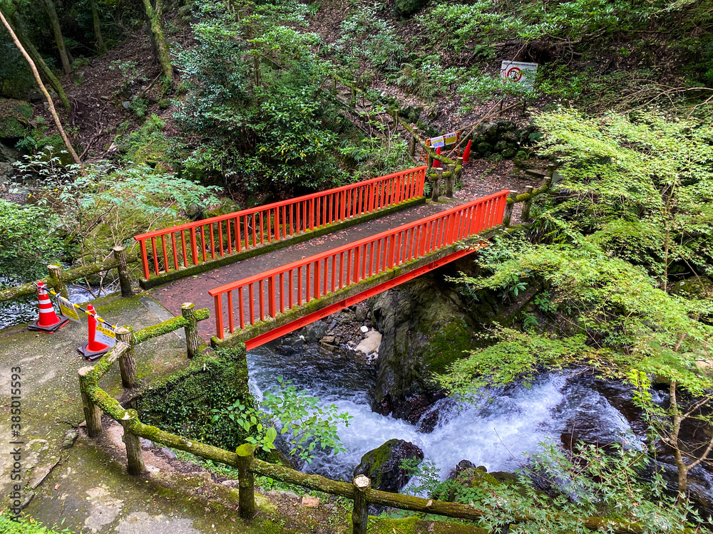 日本の山の中に流れる川の上を通る赤い小橋