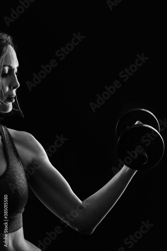 Slim athletic woman Holding dumbbell in the hand on black © katafree