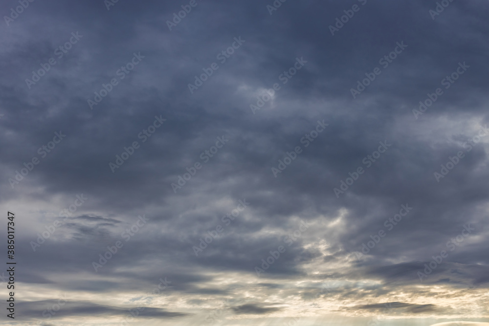 Abstract background with blue clouds in the evening in the atmosphere. The sun illuminates the clouds on the horizon.