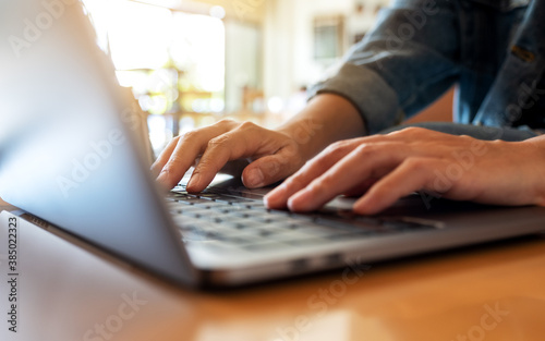 Closeup image of a woman working and typing on laptop computer keyboard on the table