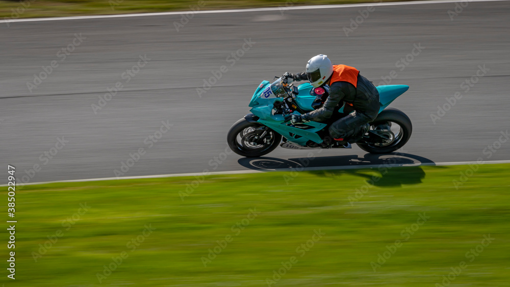 A panning shot of a racing bike cornering on a track.