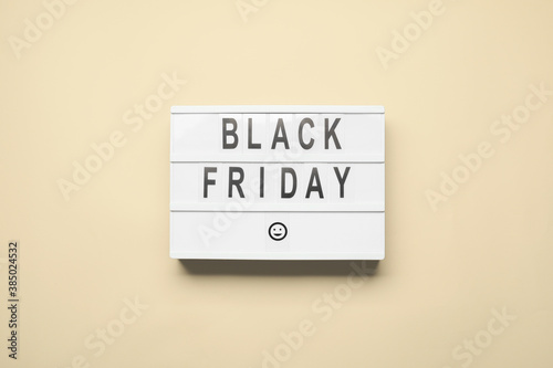 Board with text BLACK FRIDAY on color background