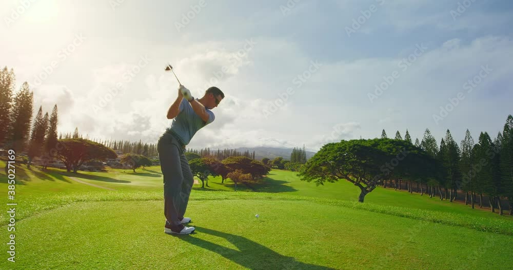 Man playing golf at sunrise, swinging and hitting golf ball, slow