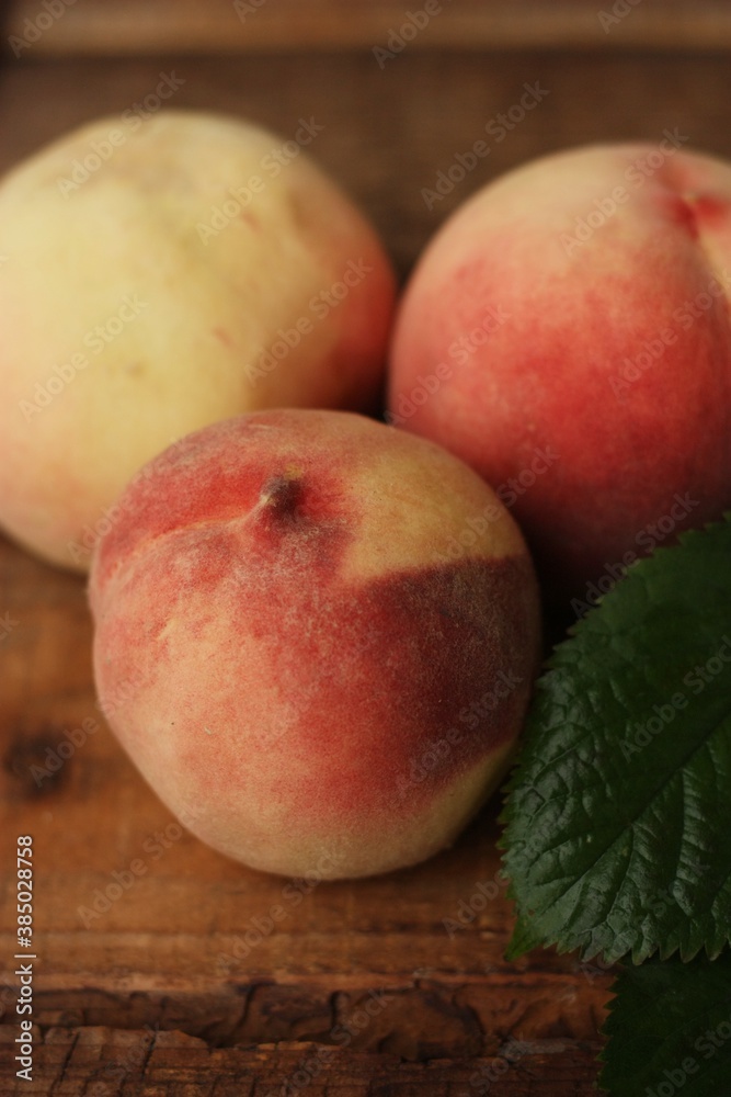 Fresh juicy peaches with leaves on the table Fresh juicy peaches with leaves on the table