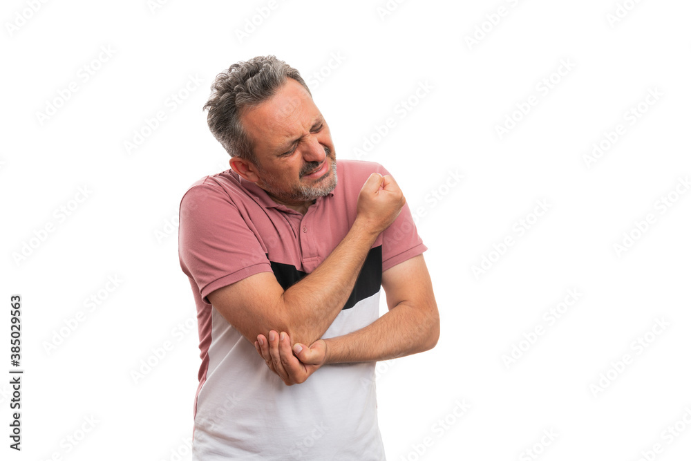 Man in tshirt with hurting expression touching painful elbow Man in tshirt with hurting expression touching painful elbow