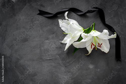 Lily funeral flower on dark stone. Condolence card with copy space photo