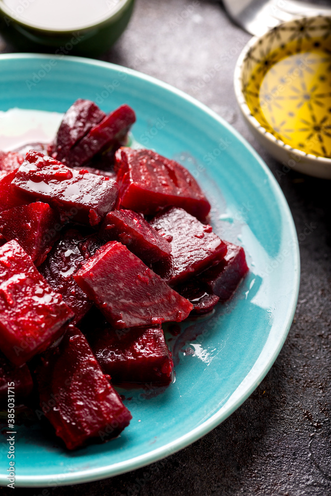 Beetroot salad with garlic and olive oil sauce in dish on dark background. Beetroot salad with garlic and olive oil sauce in dish on dark background.
