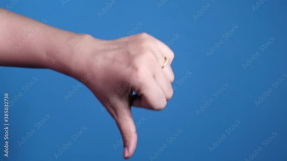 hand showing thumb down sign on blue background. hand showing thumb down sign on blue background.