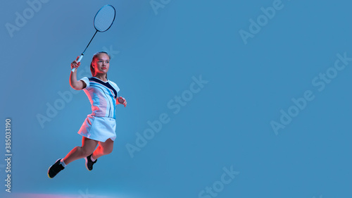 Motion. Beautiful dwarf woman practicing in badminton isolated on blue background in neon light. Lifestyle of inclusive people, diversity and equility. Sport, activity and movement. Copyspace, flyer