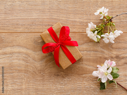 Gift box with cherry flowers on the wooden background.