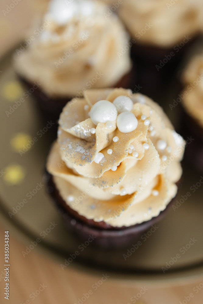 chocolate cupcakes with caramel cream decorated with silver on a gold tray