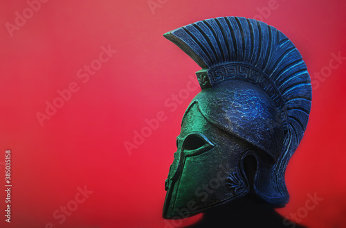 Ancient Spartan (Greek) warrior helmet on a red background with copyspace for text. Suitable for TV documentaries, history information etc. photo