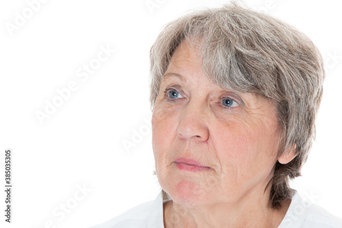 Seniorin schaut nachdenklich in die Ferne vor weißem Hintergrund