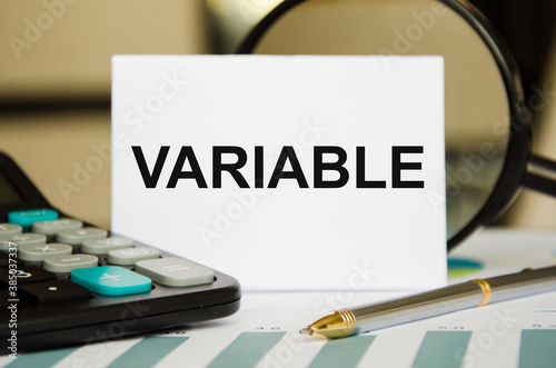 text The variable is written in a notepad. Variable universal life insurance. the text is written on a white piece of paper. in the lens of a calculator and pens