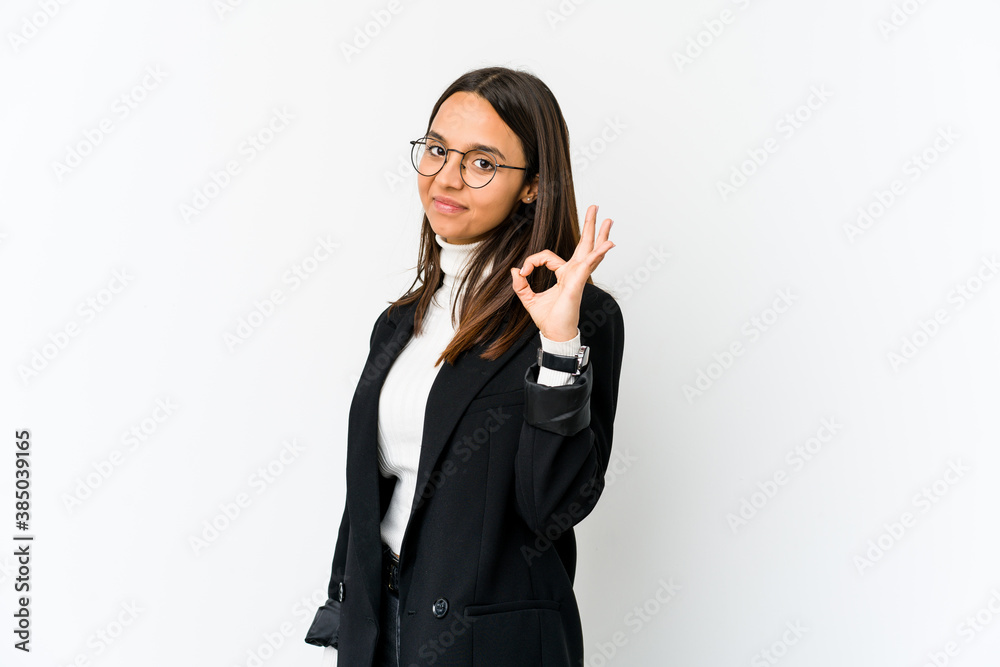 Young mixed race business woman isolated on white background winks an eye and holds an okay gesture with hand. Young mixed race business woman isolated on white background winks an eye and holds an okay gesture with hand.
