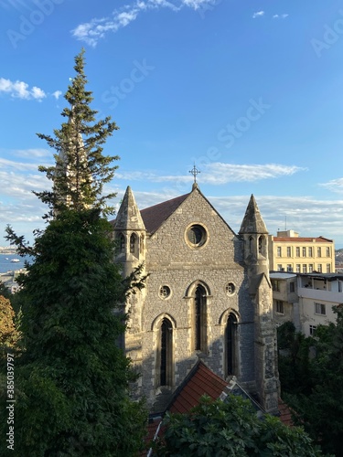 Old vintage medievel stone church building surrounded with trees. İstanbul Bosphorus at the background and ships