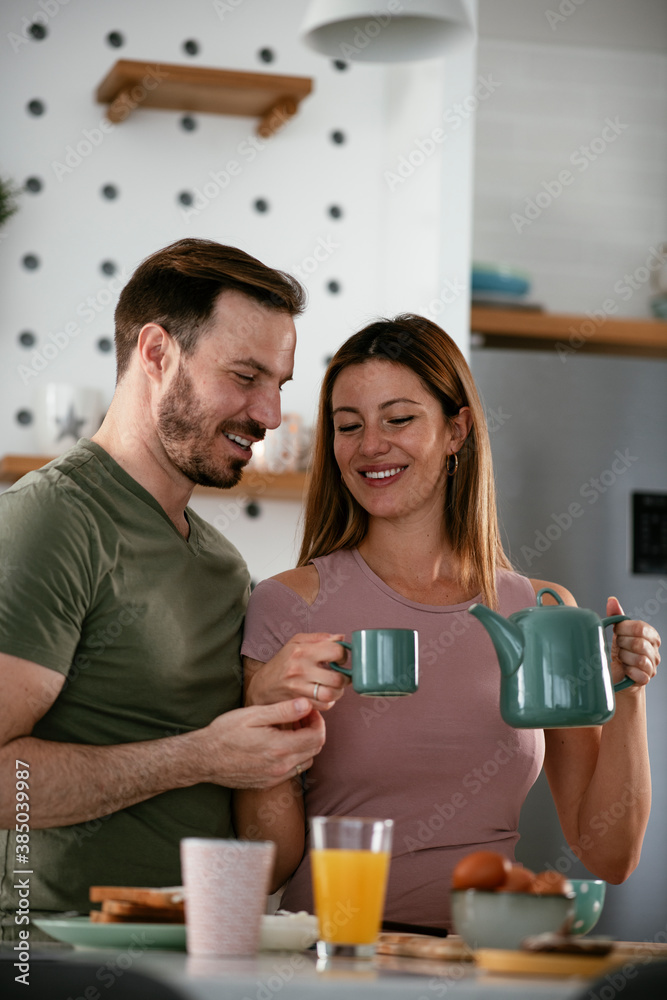 Young couple making breakfast at home. Loving couple drinking coffee in kitchen. Young couple making breakfast at home. Loving couple drinking coffee in kitchen.