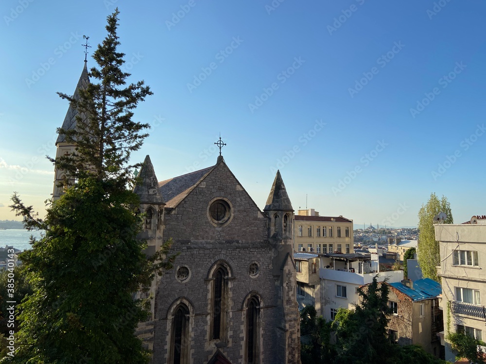 Old vintage medievel stone church building surrounded with trees. İstanbul Bosphorus at the background and ships