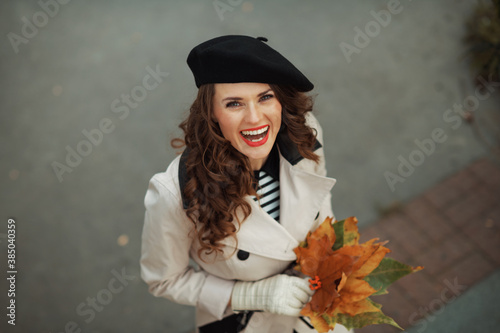 Upper view of happy 40 years old woman in beige trench coat
