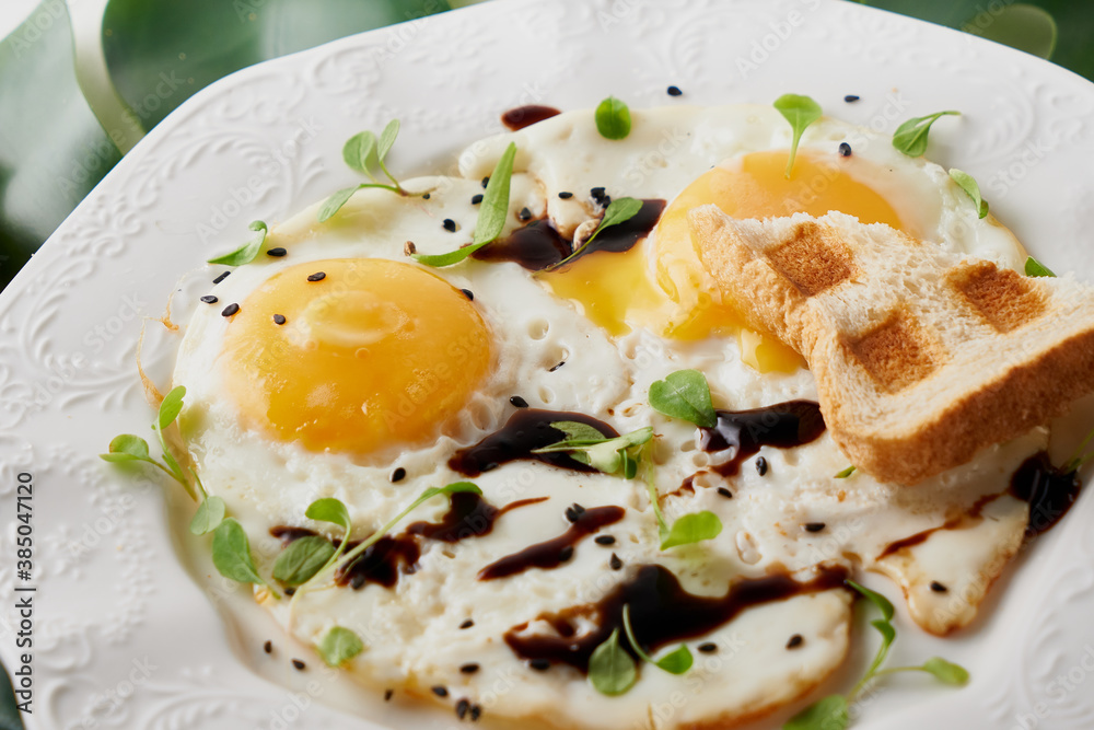 Morning breakfast with fried eggs and plant leaf on white table