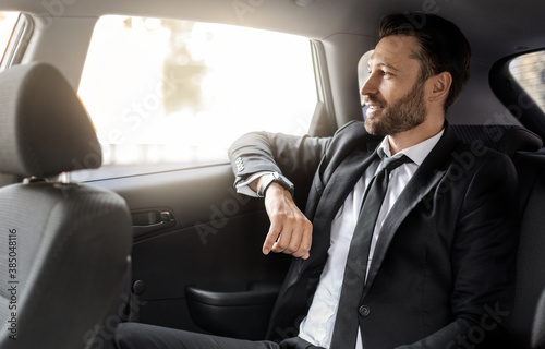 Successful businessman looking through window at car © Prostock-studio