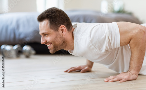 Sporty Man Doing Plank Exercise On Floor Training At Home