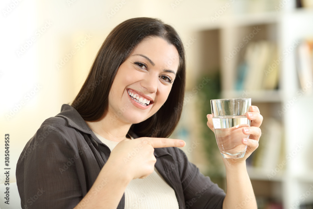 Happy woman pointing at water glass at home Happy woman pointing at water glass at home