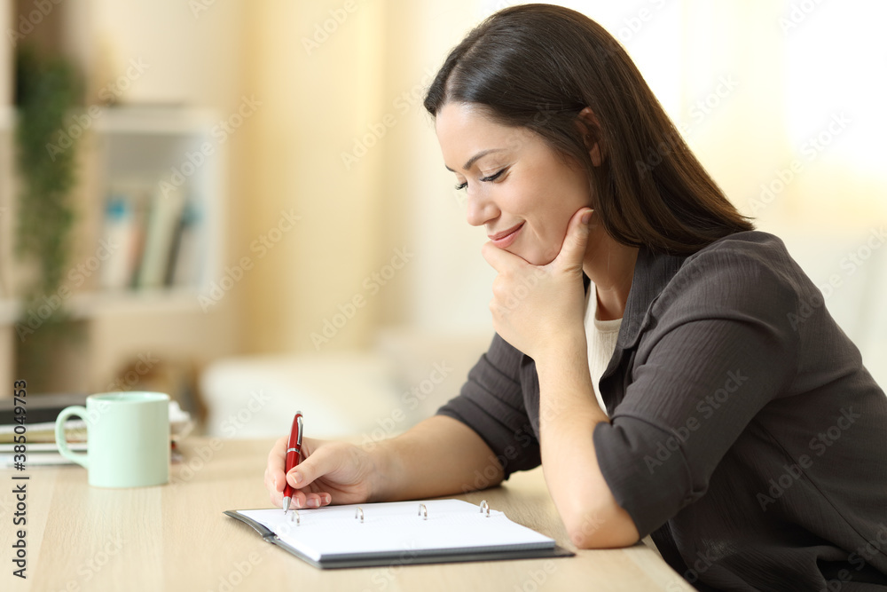 Pensive woman writing in a notebook at home Pensive woman writing in a notebook at home