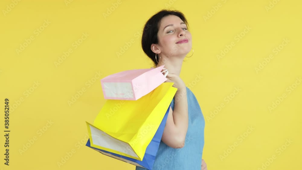 Shopaholic lifestyle. Black friday. Coquettish happy woman disappearing moved down with colorful shopping bags. Isolated on yellow copy space. Sale and discount. Cyber monday. Holiday gifts Shopaholic lifestyle. Black friday. Coquettish happy woman disappearing moved down with colorful shopping bags. Isolated on yellow copy space. Sale and discount. Cyber monday. Holiday gifts