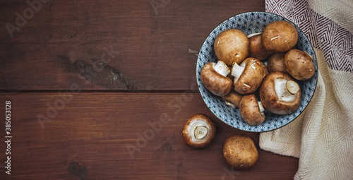 Fresh champignon portobello mushrooms in a bowl on a wooden table