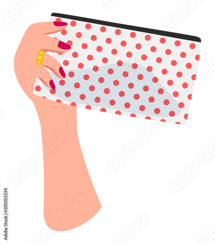 Isolated at white background white female hand with red nail polish, golden ring on finger holding dotted cosmetic bag with silhouette of cosmetics inside. Equipment of visagiste. Simple icon