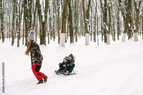 Mother sledding her kids. Family vacation on Christmas. Family having fun in winter.