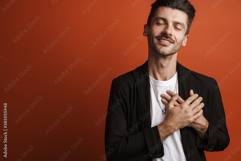 Photo of joyful handsome man smiling and keeping his hands on chest Photo of joyful handsome man smiling and keeping his hands on chest