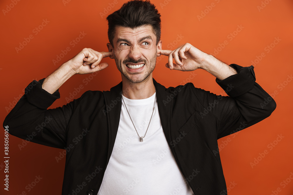 Photo of young displeased man plugging his ears with fingers