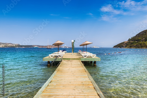Fototapeta Naklejka Na Ścianę i Meble -  Beach pier with sun umbrellas and beach loungers in Aegean sea, Golturkbuku beach, Bodrum, Turkey.