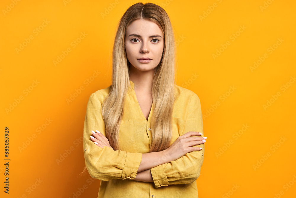 Young beautiful blonde woman in casual shirt, with crossed arms, standing against isolated yellow background, happy face, smiling, looking at camera. A positive person. Young beautiful blonde woman in casual shirt, with crossed arms, standing against isolated yellow background, happy face, smiling, looking at camera. A positive person.