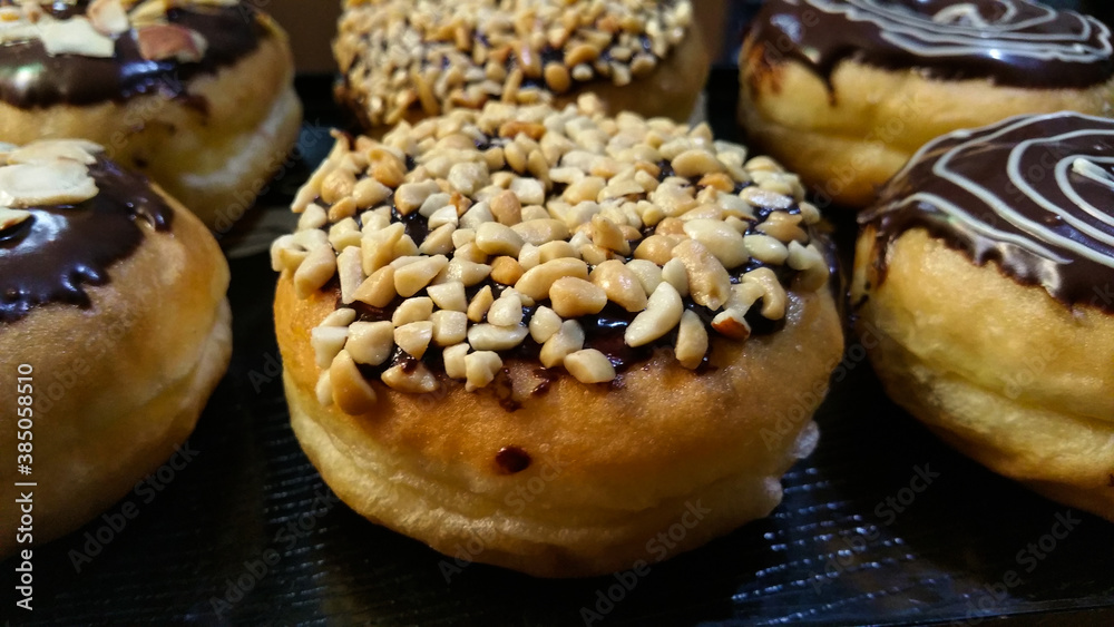Close-up of homemade chocolate donuts. Donut decorated with delicious chocolate, nuts and almonds with chocolate and sugar garnish full of creativity and delicious texture and taste Close-up of homemade chocolate donuts. Donut decorated with delicious chocolate, nuts and almonds with chocolate and sugar garnish full of creativity and delicious texture and taste