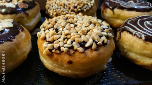 Close-up of homemade chocolate donuts. Donut decorated with delicious chocolate, nuts and almonds with chocolate and sugar garnish full of creativity and delicious texture and taste