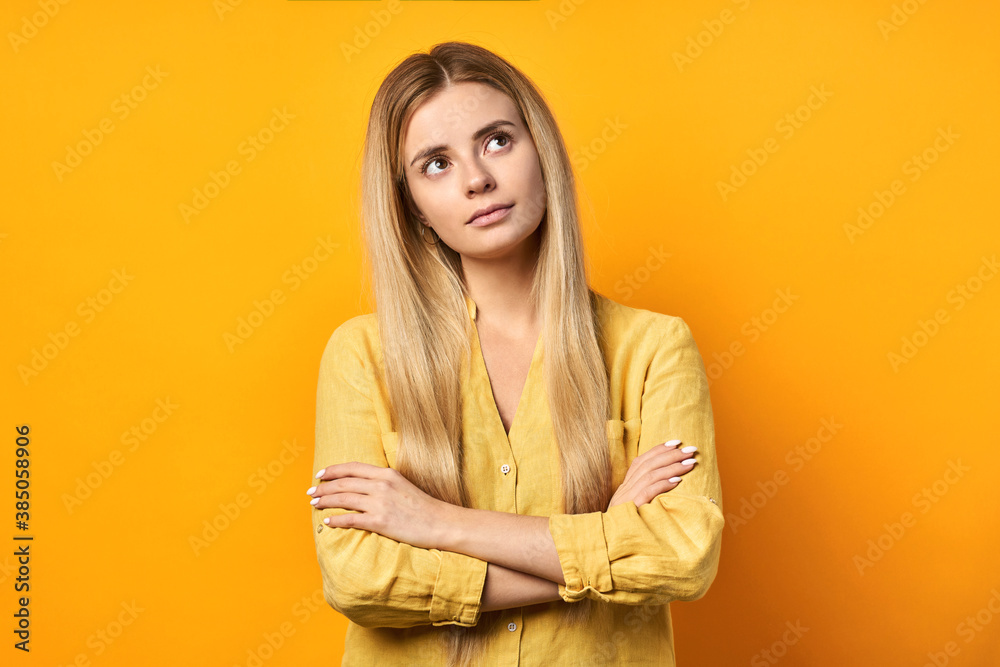 Young beautiful blonde woman in casual shirt, with crossed arms, standing against isolated yellow background, happy face, smiling, looking at camera. A positive person. Young beautiful blonde woman in casual shirt, with crossed arms, standing against isolated yellow background, happy face, smiling, looking at camera. A positive person.