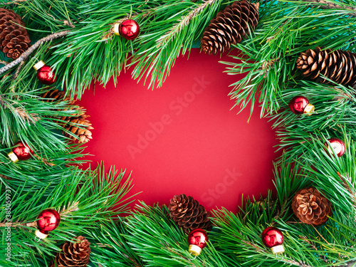 Creative layout of Christmas tree branches and cones on a red background, top view, copy space, flat layout. The concept of New year and Christmas. Bright new year background or greeting card