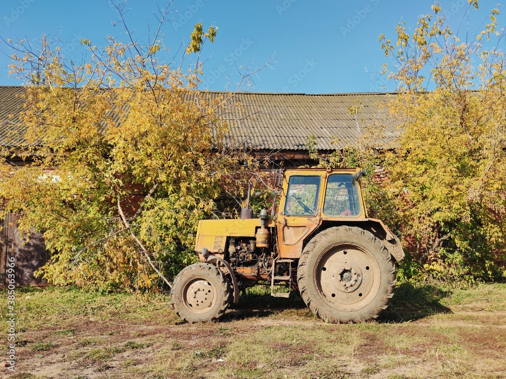 autumn landscape with old yellow tractor near trees autumn landscape with old yellow tractor near trees