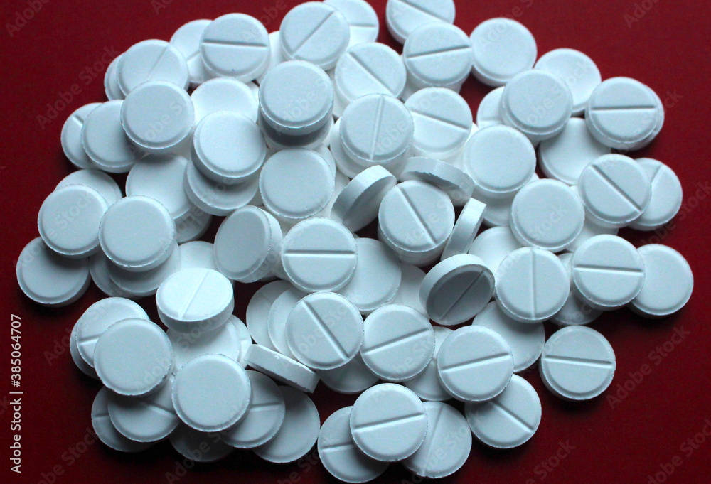 White round pills on red background White round pills on red background