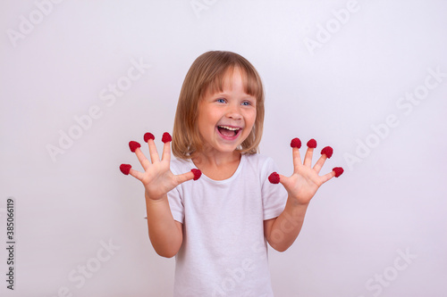 Funny happy cute girl with raspberries on her fingers.